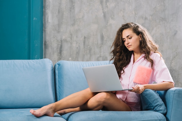 Jonge vrouw zittend op de Bank met behulp van laptop