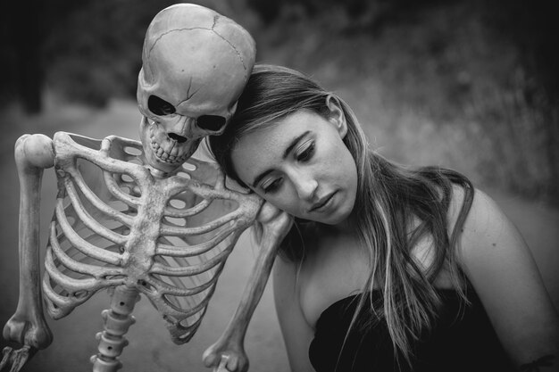 Jonge vrouw zittend op de weg met skelet en naar beneden te kijken