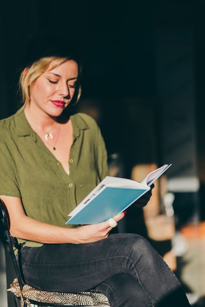 Jonge vrouw zittend op een stoel met boek