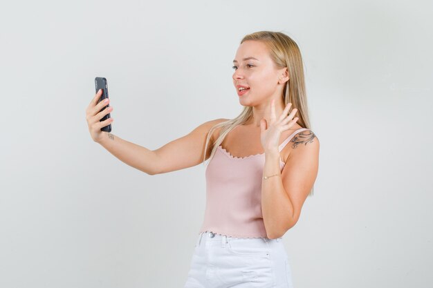 Jonge vrouw zwaaiende hand op videocall in hemd