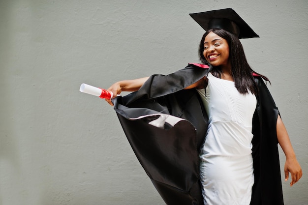 Jonge vrouwelijke Afro-Amerikaanse student met diploma poseert buitenshuisxA