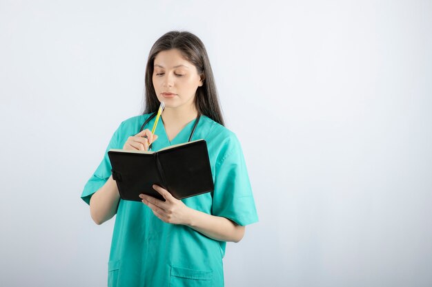 jonge vrouwelijke arts die zich met notitieboekje en potlood bevindt.