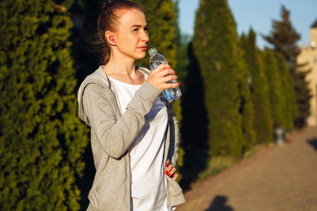 Jonge vrouwelijke atleet jogt in de stadsstraat in de zon