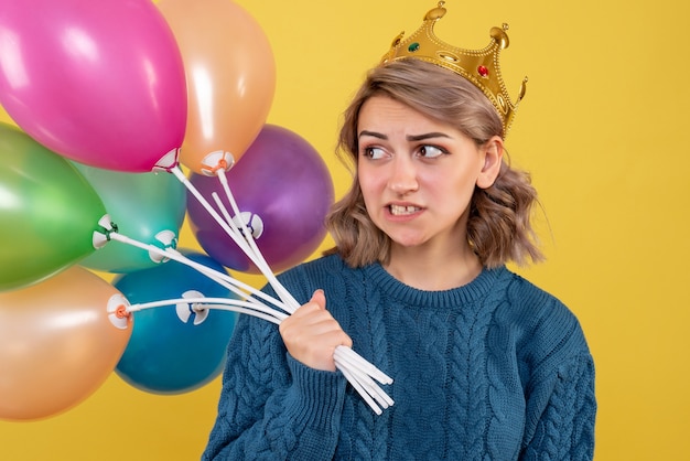 jonge vrouwelijke bedrijf ballonnen in kroon op geel