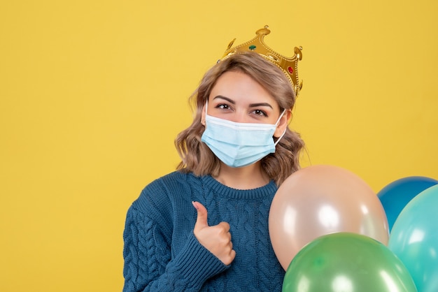 jonge vrouwelijke bedrijf ballonnen in steriel masker op geel