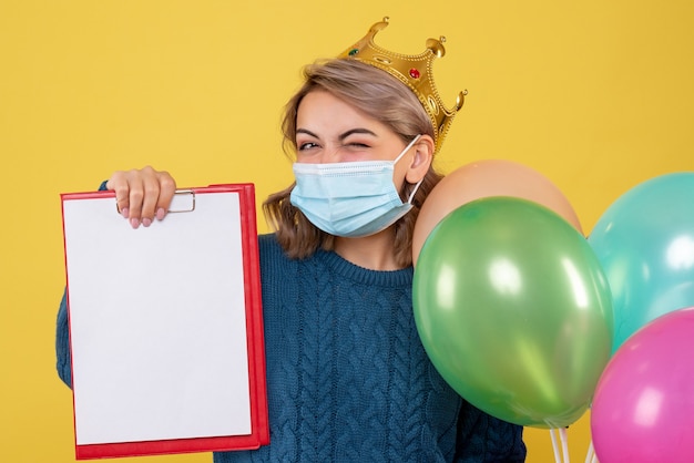 jonge vrouwelijke bedrijf ballonnen in steriel masker op geel