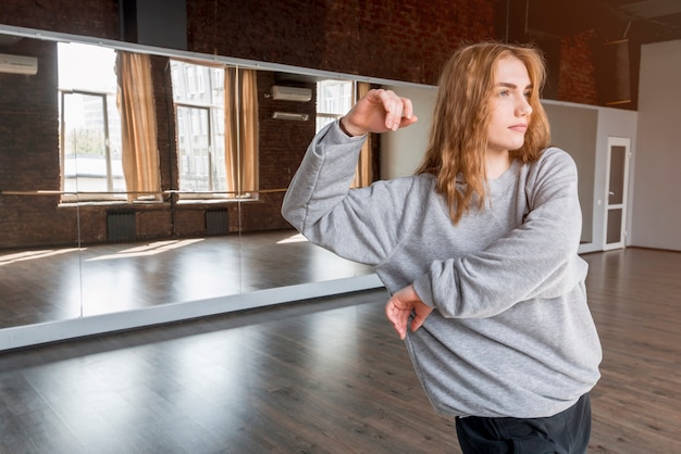 Jonge vrouwelijke danser die voor spiegel praktizeert