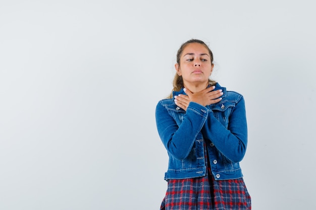 Jonge vrouwelijke hand in hand gekruist op nek in shirt, jasje en op zoek boos. vooraanzicht.