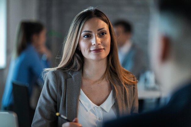 Jonge vrouwelijke ondernemer die met een collega praat terwijl hij op kantoor is