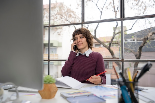 Jonge vrouwelijke ontwerper die aan de telefoon praat