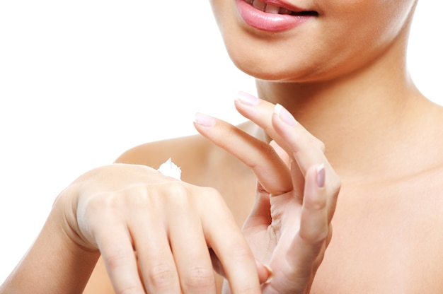 Jonge vrouwelijke persoon zorg van haar handen cosmetische crème toe te passen