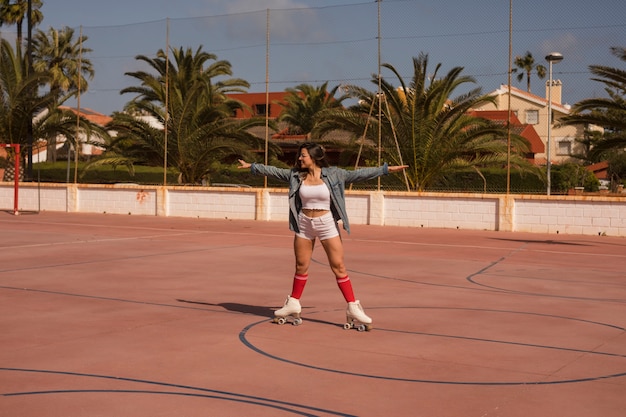 Gratis foto jonge vrouwelijke schaatser die op een openluchthof uitoefent