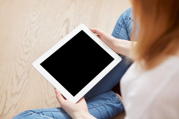 Jonge vrouwelijke studentenzitting in een universitaire recreatiezaal die touchpad gebruikt