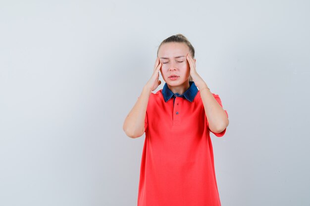 Jonge vrouwelijke tempels wrijven en hoofdpijn hebben in t-shirt vooraanzicht.