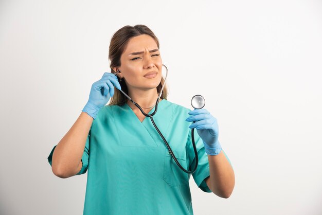Jonge vrouwelijke verpleegster die op stethoscoop kijkt.