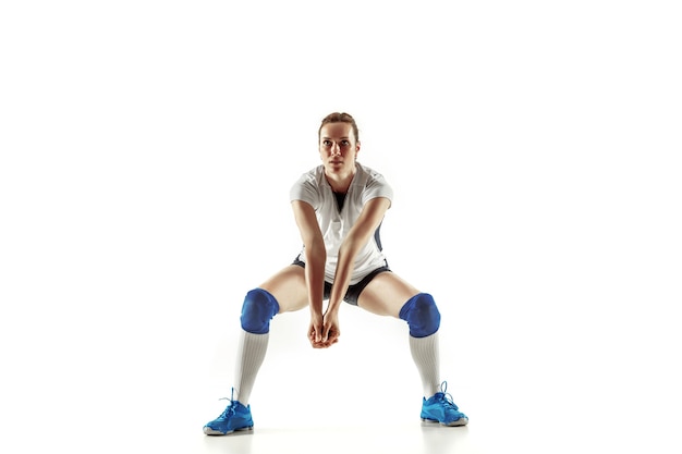 Jonge vrouwelijke volleyballspeler die op witte studioachtergrond wordt geïsoleerd. vrouw in sportuitrusting en schoenen of sneakers trainen en oefenen. concept van sport, gezonde levensstijl, beweging en beweging.