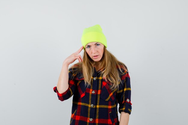 Jonge vrouwelijke vrouw in een geruit overhemd met een hoed