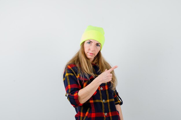 Gratis foto jonge vrouwelijke vrouw in een geruit overhemd met een hoed