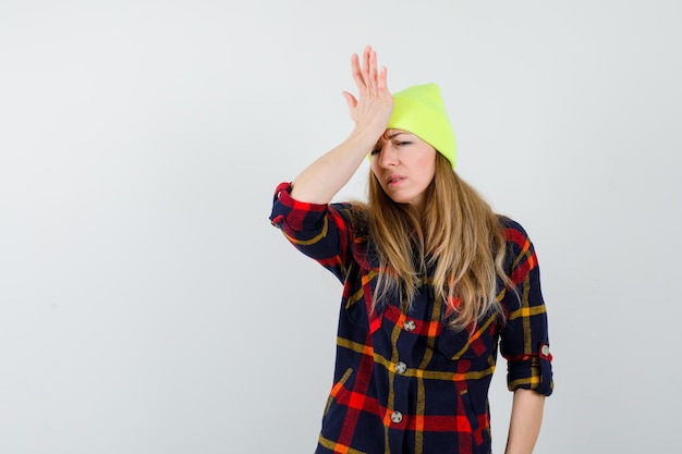 Gratis foto jonge vrouwelijke vrouw in een geruit overhemd met een hoed