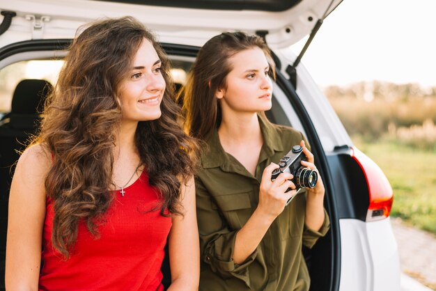 Jonge vrouwen die beelden dichtbij auto nemen