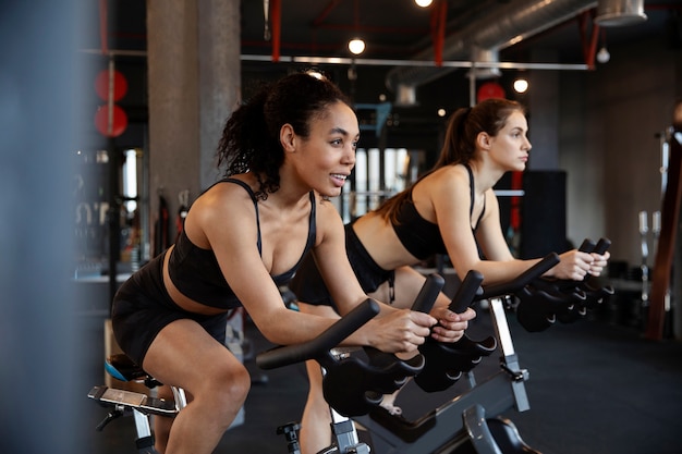 Gratis foto jonge vrouwen die deelnemen aan spinningles