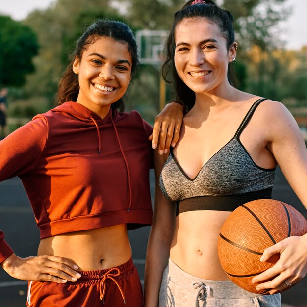 Jonge vrouwen die met een basketbal stellen