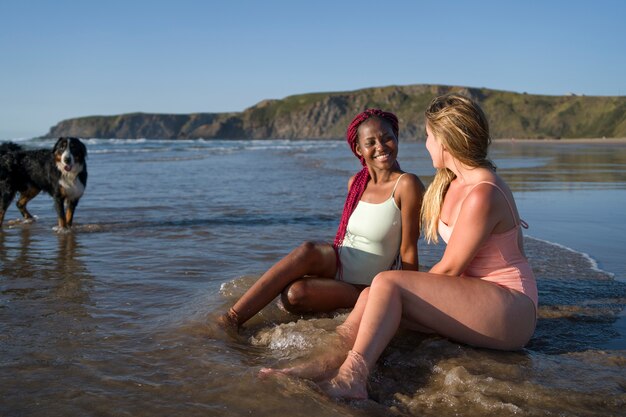 Jonge vrouwen die plezier hebben met de hond op het strand