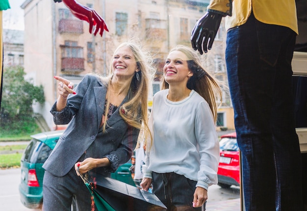 Jonge vrouwen die van het venster winkelen genieten