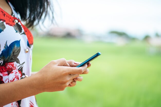 Jonge vrouwen dragen kleurrijke kleding en spelen een smartphone