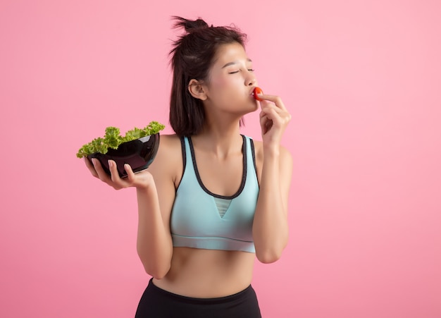 Jonge vrouwen eten graag groenten op een roze.