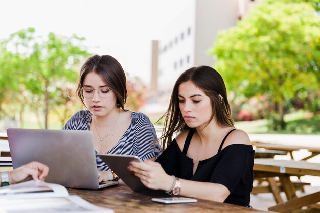 Jonge vrouwen met behulp van gadgets aan tafel