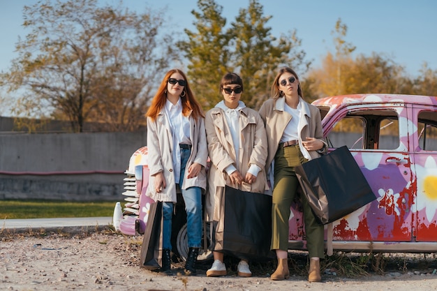 Jonge vrouwen poseren in de buurt van een oude versierde auto