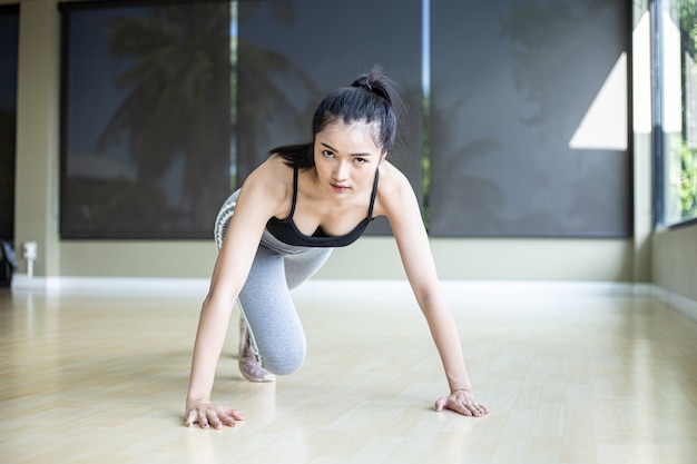 Jonge vrouwen worden opgewarmd voordat ze gaan sporten door de vloer te duwen en zijn knieën in de sportschool te buigen.