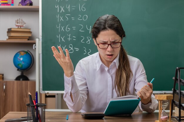 Jonge vrouwenleraar die glazen draagt die notitieboekje houdt