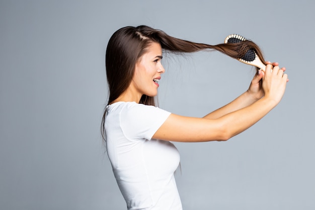 Jonge vrouwenproblemen met haar, gespleten zwak haar, verward haar dat op grijs wordt geïsoleerd