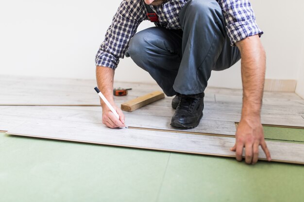 Jonge werknemer die een vloer bekleedt met gelamineerde vloerplanken
