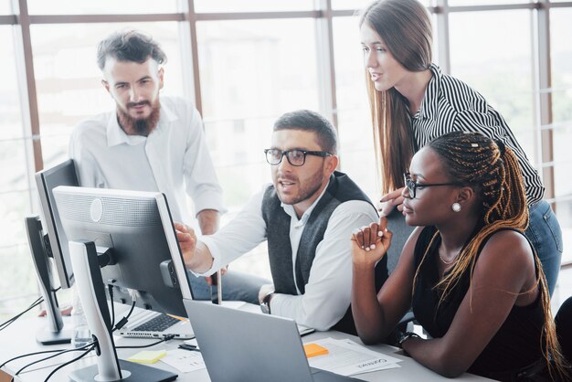 Jonge werknemers die in het bureau bij de lijst zitten en laptop, een concept van de de brainstormingsvergadering van het teamwerk met behulp van.