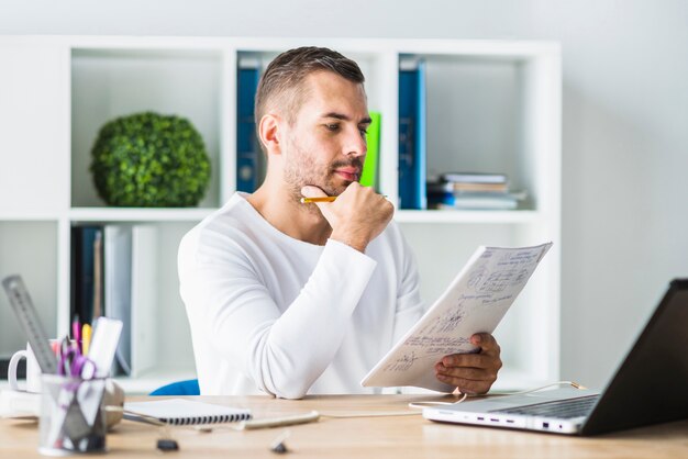 Jonge zakenman die document in bureau bekijkt