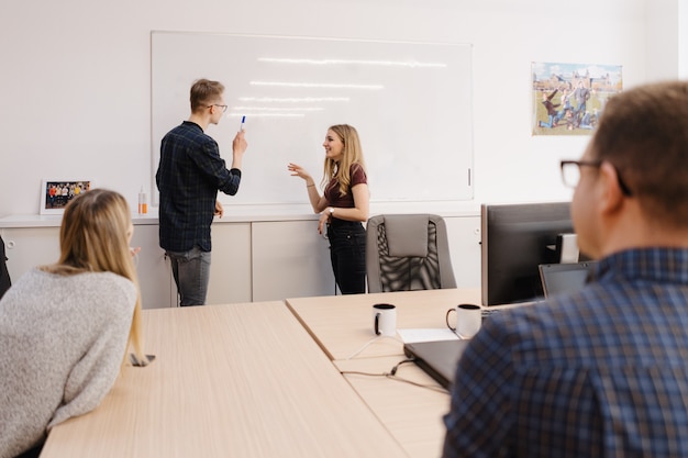 Jonge zakenman die met collega's over whiteboard op kantoor bespreken