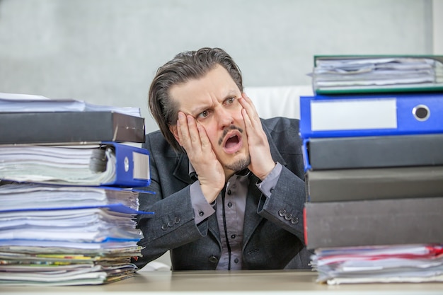 Jonge zakenman die vanuit zijn kantoor werkt - het concept van stress