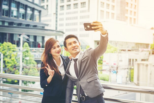 Jonge zakenman en collega buitenshuis in stedelijke omgeving nemen een selfie