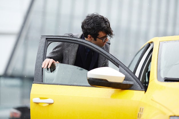 Gratis foto jonge zakenman getting in taxi