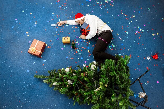 Jonge zakenman het vieren Kerstmis in bureauslaap op vloer.