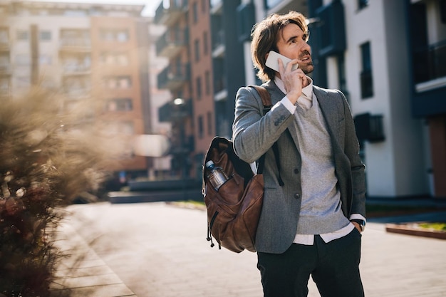 Jonge zakenman praten op mobiele telefoon terwijl hij op straat staat.