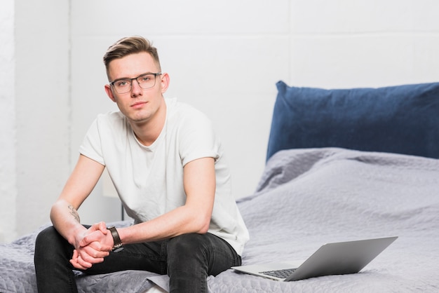 Jonge zakenman zittend op bed met een open laptop