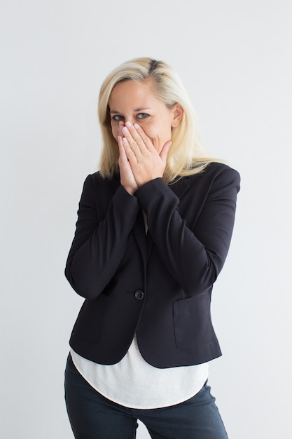 Jonge zakenvrouw chuckling bedekt mond