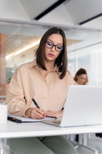 Jonge zakenvrouw die aan haar bureau werkt met laptop