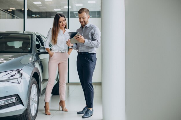 Jonge zakenvrouw die een auto koopt in de autoshowroom