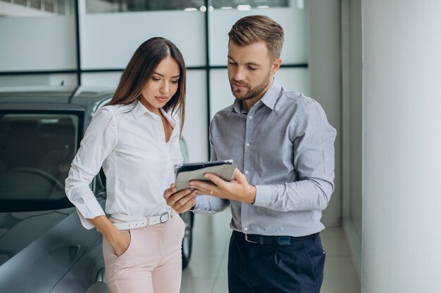 Jonge zakenvrouw die een auto koopt in de autoshowroom