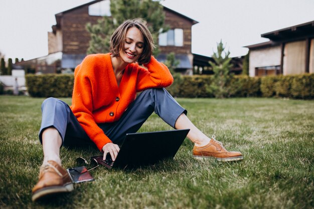 Jonge zakenvrouw met laptop op het gras